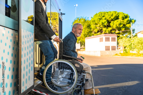 Caregiver helping man in wheelchair boarding bus