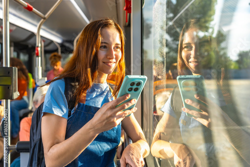 Foto Young woman smiling, watching phone through bus window