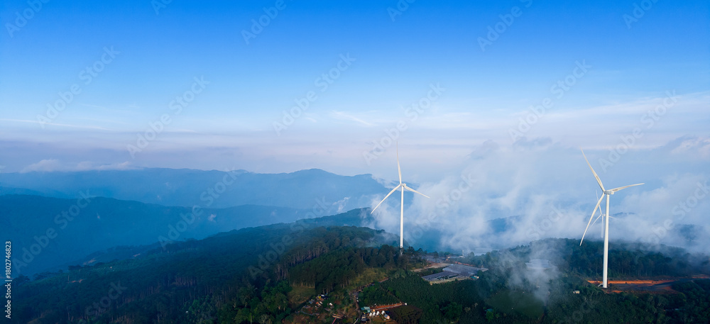 Obraz premium Wind generators with fog and clouds in mountains of Vietnam, industry landscape. Banner Turbines for eco renewable electric power production