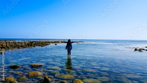 Obraz na plátně Embracing the horizon, a lone traveler stands in the crystal clear shallows of a