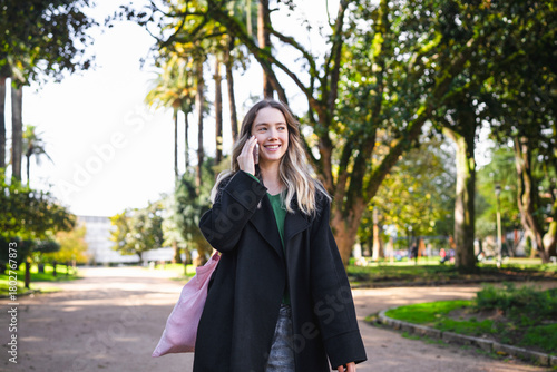 Young woman walking in park talking on phone