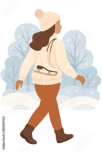 A beautiful woman wearing a white sweater and hat, with ice skates on her back, walks through a snowy winter park