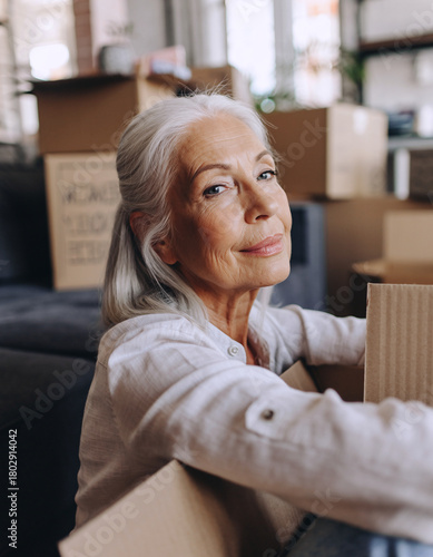 Senior woman moving home, lifestyle packing boxes with warm natural light