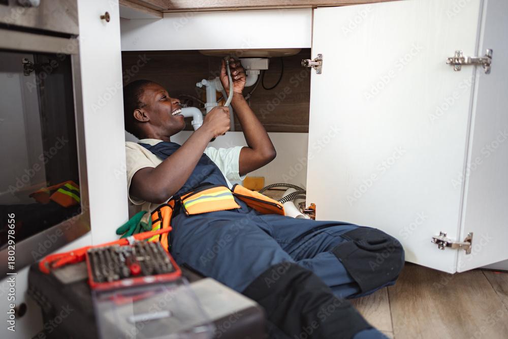 © Jelena - Plumber fixing pipes under kitchen sink