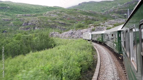 The Flåmsbana train in Norway as it travels through lush green mountains and waterfalls view from inside a carriage. Smooth cinematic motion and authentic nature atmosphere