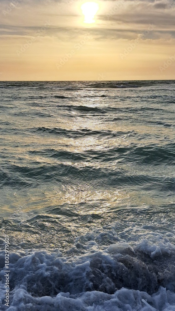 Obraz premium Sunset Over Ocean Waves with Golden Sky