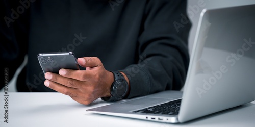 A middle-aged man holds a smartphone in his hand for various transactions such as paying for products online, shopping online, checking information, and more.