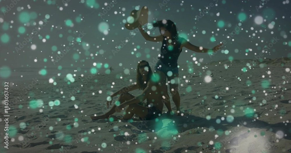 Fototapeta premium Sitting couple in dark swimwear soaking sun on sandy beach, with sunhat towel shades teal bokeh