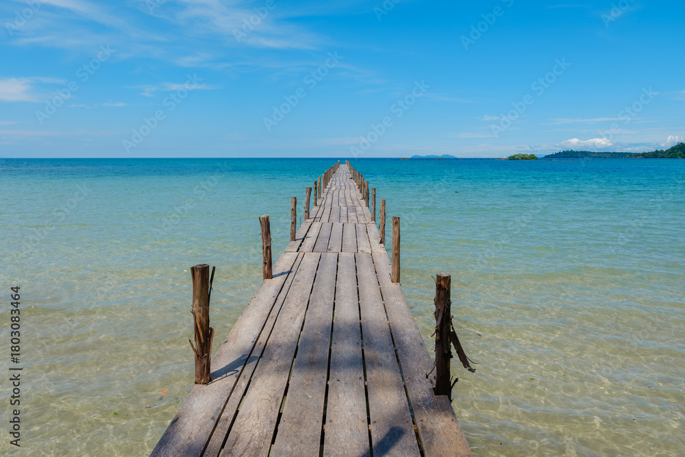 Fototapeta premium Tranquil wooden pier extending into the clear blue waters of Koh Kood Island in Thailand