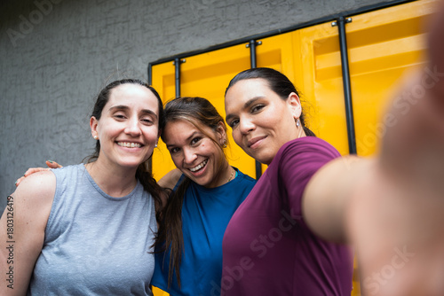 Three latin hispanic women friends smiling and taking a selfie, celebrating fitness and healthy lifestyle after a workout