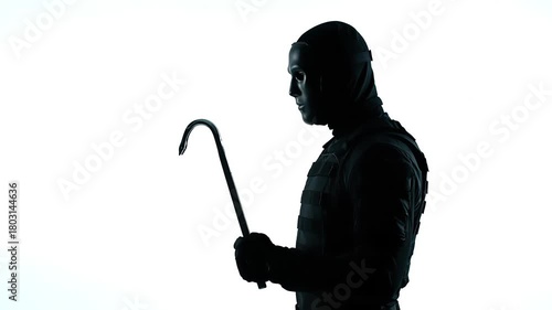 Silhouette of Masked Figure Holding Crowbar Against Bright White Background