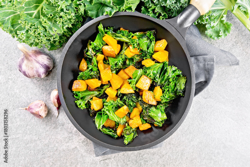 Kale with pumpkin in skillet on stone countertop top