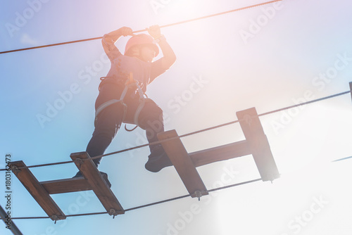 Child boy in Protective Gear Navigating a High Ropes Course in adventure park 