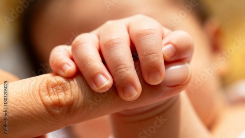 close view of a baby hand holding a finger of its mom, hand of a baby, haptic