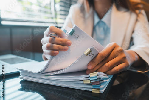 Close-up of a professional organizing documents at a desk, showcasing efficient office work and organization.