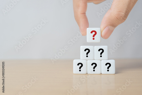 Hand hold dice in question mark mean what on wooden table background, column of wooden blocks with question sign mark. copy space,FAQ frequently asked questions, Answer, Information
