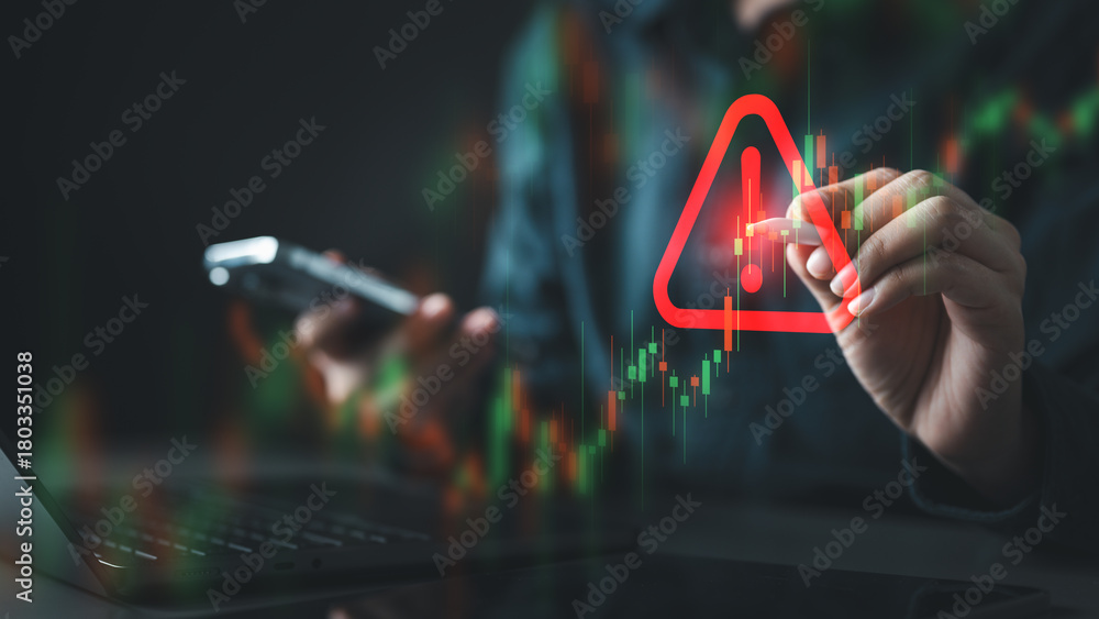 Fototapeta premium A person analyzing a trading chart with a glowing warning symbol, representing market volatility, investment risk, financial decline, and strategic decision-making during crisis situations.