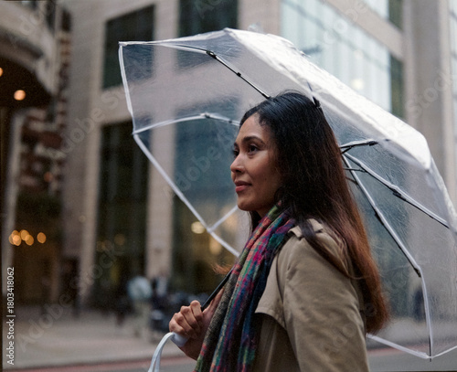 Thoughtful philippine woman walking city street with umbrella