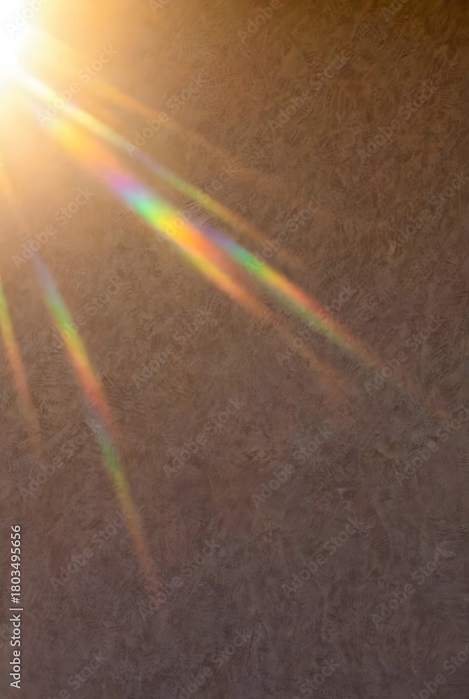 Naklejka premium Warm sun flare with rainbow rays on textured wall