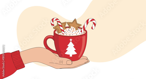 A hand in a red sweater holds a festive red Christmas mug filled with creamy hot chocolate, garnished with whipped cream, gingerbread star cookies, and candy canes.
