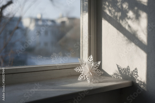 delicate paper snowflake rests on frosted window its intricate patterns beautifully illuminated by gentle sunlight