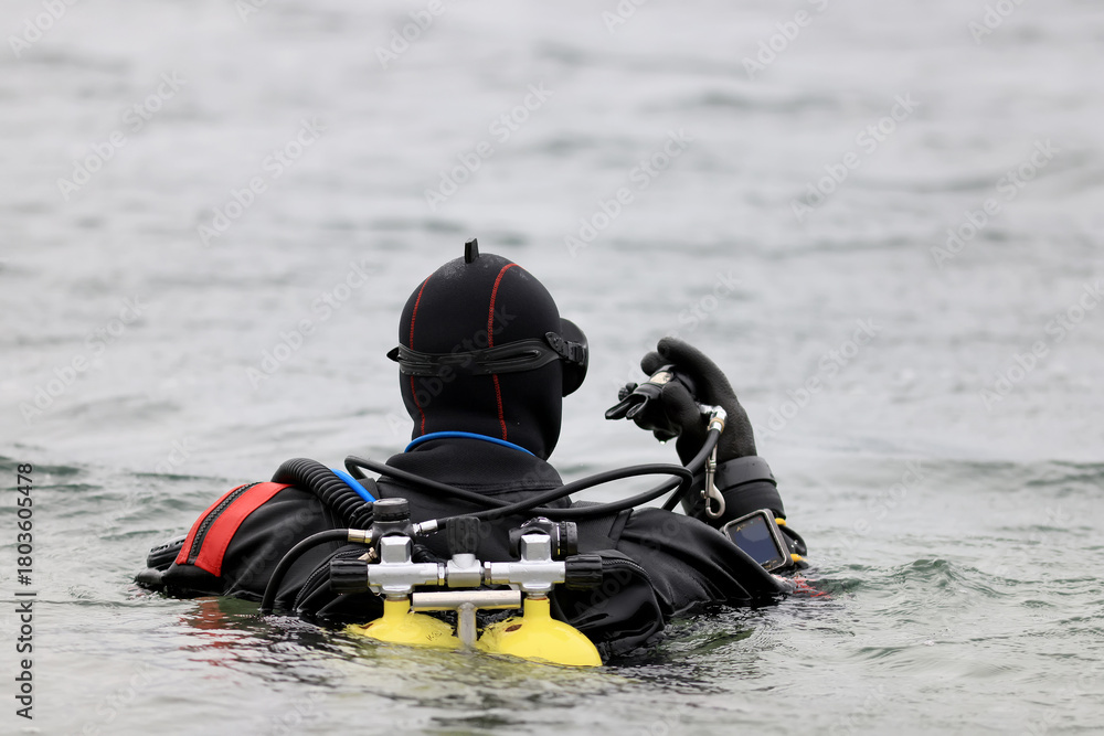 Naklejka premium Diver in a dry suit prepares to dive into cold water, extreme diving