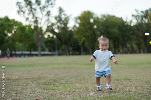 Happy baby running freely on green grass