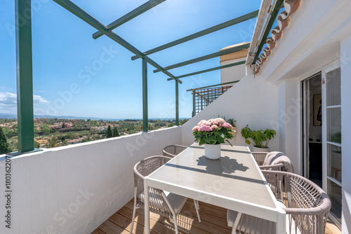 Outdoor terrace with dining table and chairs overlooking a scenic mediterranean landscape