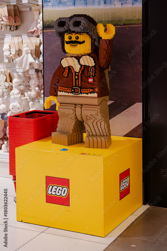 Naklejka premium LEGO aviation-themed figure statue displayed on branded pedestal in toy retail area - Amsterdam, Netherlands - November 13 2025