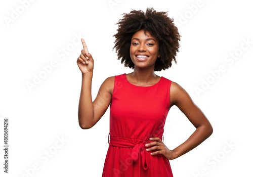 A cheerful young black woman with an afro hairstyle wearing a vibrant red dress points her finger upwards isolated on transparent background