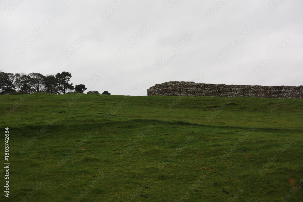 Obraz premium Landscape view of ancient monument Hadrian’s Wall. the rugged Scottish highland countryside, a dramatic historical landmark set against a windswept moorland backdrop