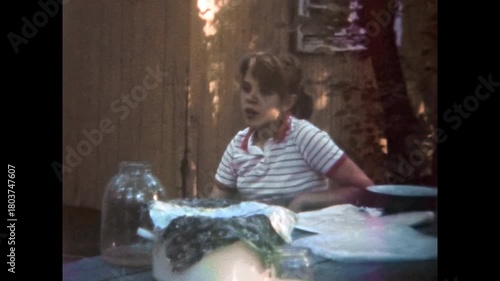 Youthful boredom. Young bored girl sitting at picnic table outdoors, talking and relaxing. Mental health problem of female kid. Depressed teenager. Old film. Archival retro 1960s. Vintage archive.