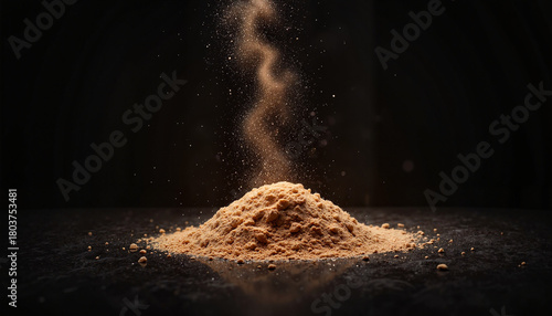 A pile of brown powder creating a swirling effect in the air against a dark background