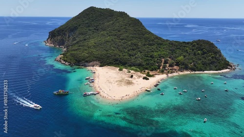 Aerial drone cinematic video of scenic caves and turquoise beach in paradise island of Marathonisi in bay of Laganas, visited by small boats a true tourist attraction, Zakithnos island, Ionian, Greece