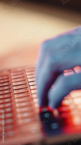 A close-up shot captures a mans hands actively typing on a laptop. The background is blurred and bathed in cinematic blue light, highlighting the hands and keyboard.