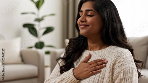 A young woman practices a deep breathing exercise with her hand on her chest. Managing stress and anxiety through mindfulness. Mental health and self-care concept