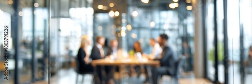 blurred background of a business meeting in a modern office with a glass door and people sitting at a table, a group talking during a conference or meeting.