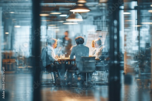 blurred background of a business meeting in a modern office with a glass door and people sitting at a table, a group talking during a conference or meeting.