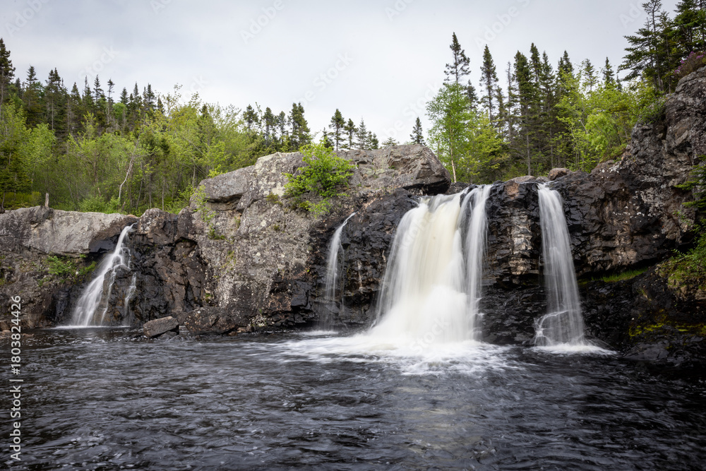 Fototapeta premium Waterfall Cascading Over Rock Formations into a Quiet Pool