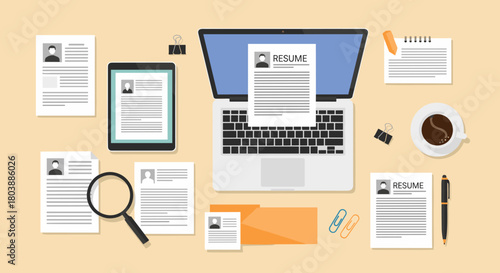 Job application process with resume documents displayed on a desk, including a laptop, tablet, and magnifying glass for review.