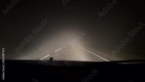 Night drive through heavy fog on an empty rural highway — low visibility road conditions captured from inside a car, concept of danger, isolation, and mystery