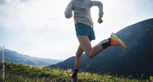 Trail runner running on the high altitude grassland mountain top trail