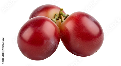 A close up of three red grapes clustered together on a black background in a studio setting