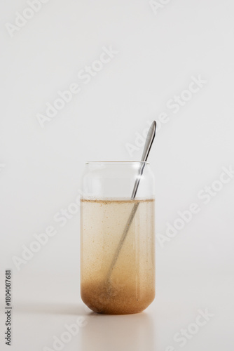 Psyllium in a glass of water with a silver spoon on a white background.