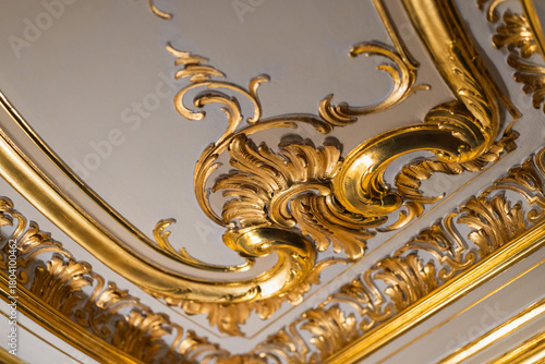 Close-up of an opulent gilded ceiling detail with ornate scroll work and gold leaf trims