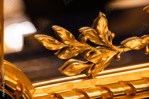 Luxurious gilded leaf motif decorates a mirror frame, close up