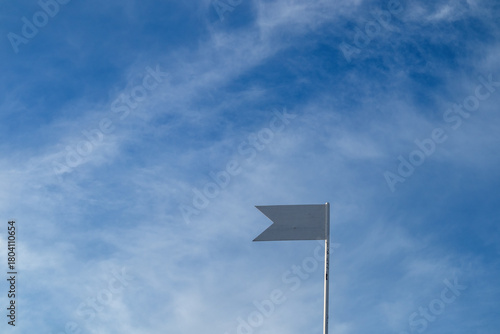 a simple metallic weather vane against blue sky, copy space