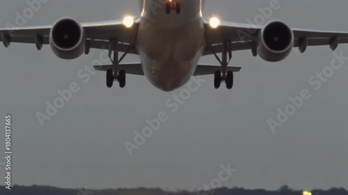 A large commercial airplane is seen taking off from a runway with landing lights on.