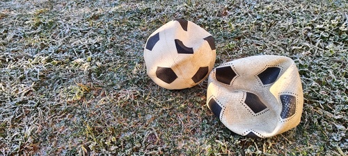 Two old deflated soccer balls on frosty grass in the cold winter morning. Abandoned footballs on a frozen field representing the end of a season