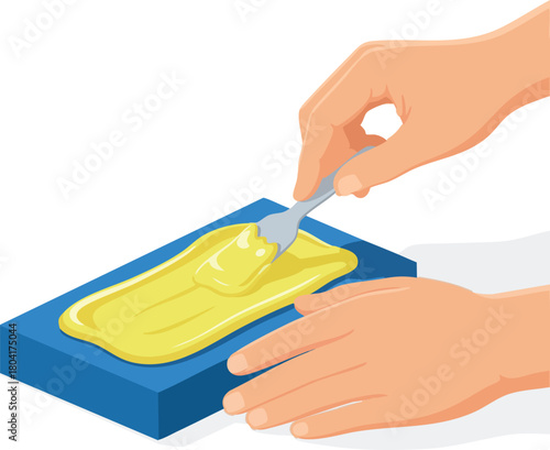 Hands applying a yellow creamy substance onto a rectangular blue surface using a small metal spatula